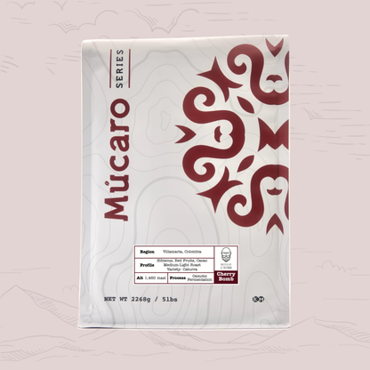 A package of Mucaro Series coffee of Cherry Bomb from Colombia, featuring a white bag with a dark red snake graphic and product details on a light pink background.