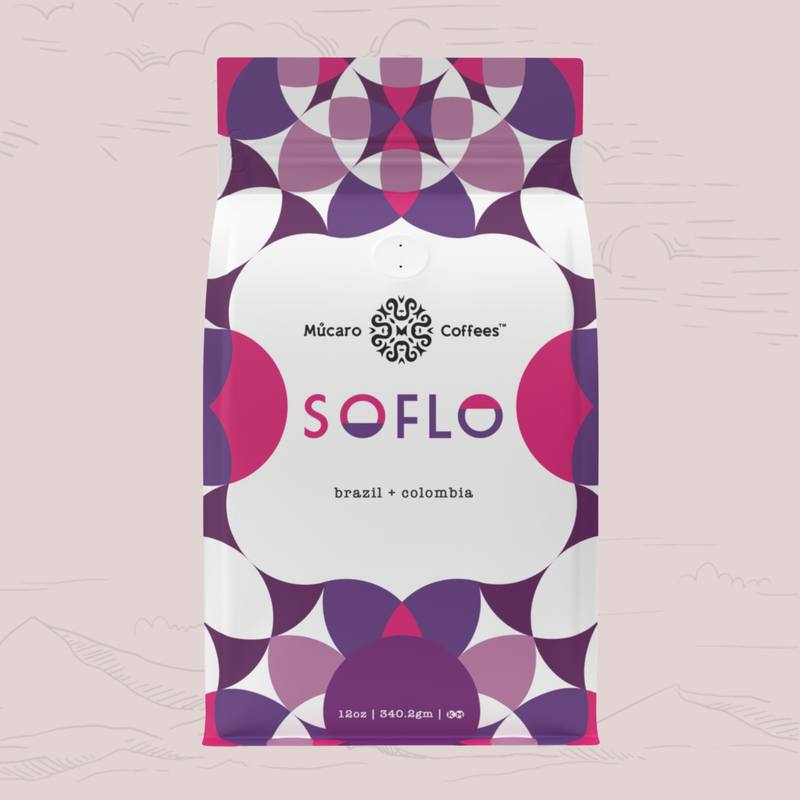 A 12oz bag of Múcaro Coffees Soflo Blend from Colombia and Brazil, featuring a modern geometric pattern in purple, magenta, and white on a light pink background.